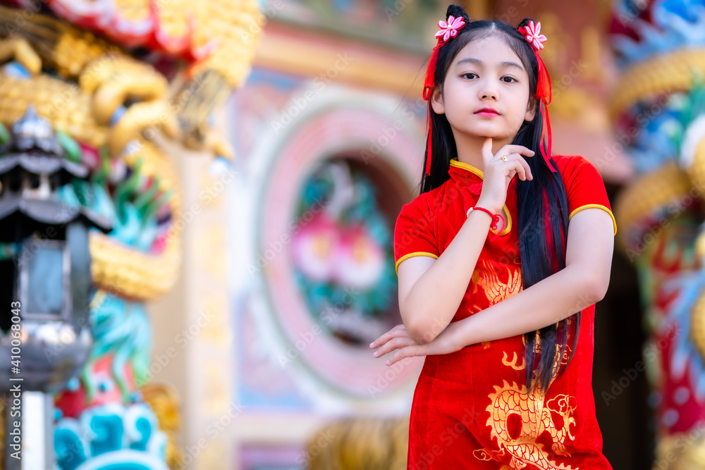 Fototapeta premium Portrait beautiful smiles Cute little Asian girl wearing red traditional Chinese cheongsam decoration for Chinese New Year Festival at Chinese shrine