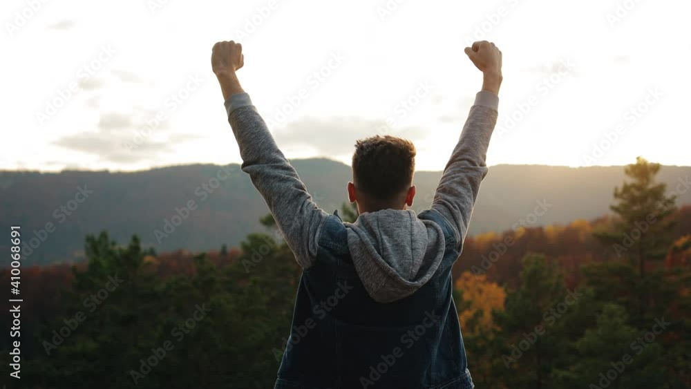 The man is happy and raising his hands in the air. He is standing on top of a mountain. Hiking in the mountains. 4K. The man is happy and raising his hands in the air. He is standing on top of a mountain. Hiking in the mountains. 4K.