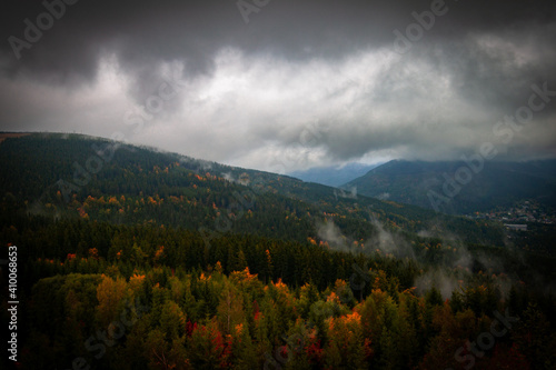 Paysage de montagne avec la forêt de tous les verts possibles, un ciel nuageux et bleu. La forêt est composée principalement de résineux, épicéas sapins et pins. photo