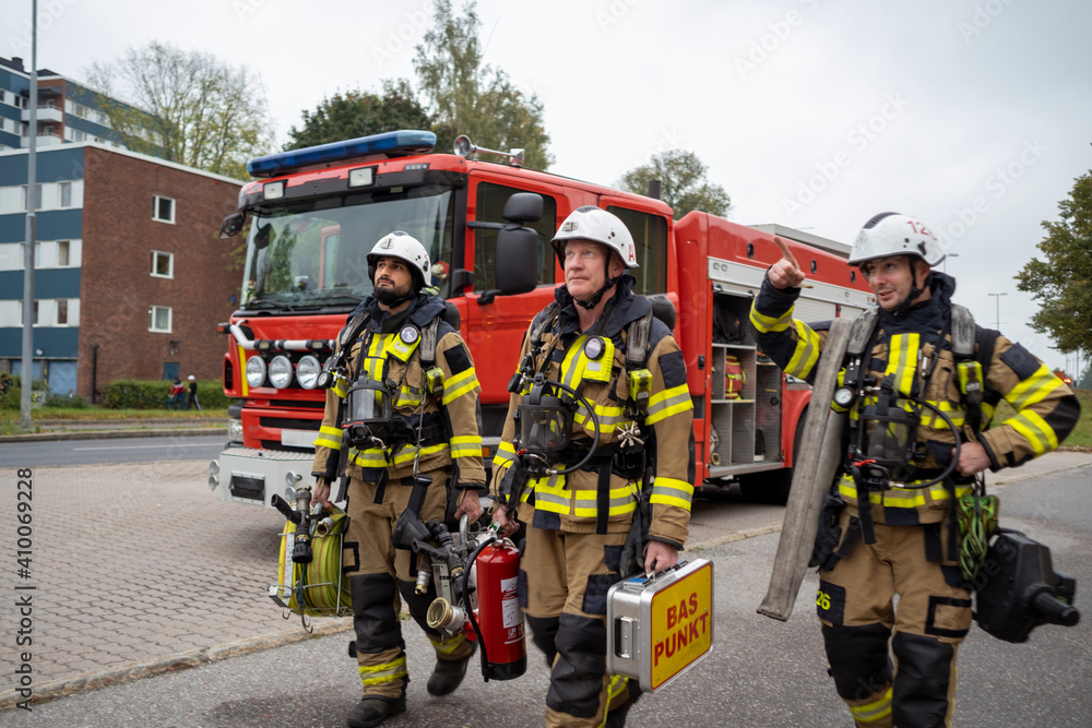 Firefighters walking, fire engine in background Firefighters walking, fire engine in background