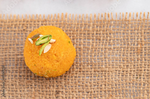 Top View Of Single Piece Indian Mithai Motichoor Ladoo Or Motichur Laddu Indian Sweet Mithai On Burlap Jute Fabric. Meetha Laddoo Is Made Of Bengal Gram Flour Deep Fried In Shuddha Desi Ghee