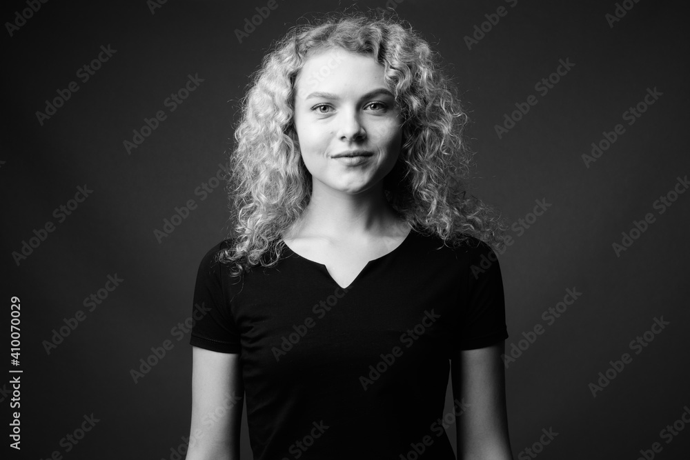 Young beautiful woman with curly blond hair against gray background Young beautiful woman with curly blond hair against gray background