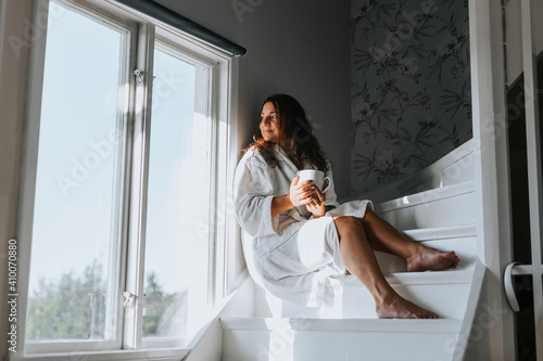 Woman sitting on stairs and looking through window photo