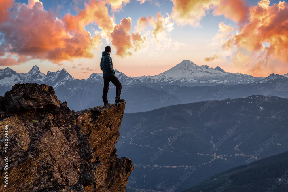 Fototapeta Adventurous man is standing on top of the mountain and enjoying the beautiful view. Taken on top of Cheam Peak in Chilliwack, East of Vancouver, BC, Canada. Colorful Sunset Sky Art Render