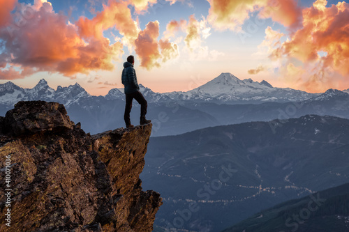 Adventurous man is standing on top of the mountain and enjoying the beautiful view. Taken on top of Cheam Peak in Chilliwack, East of Vancouver, BC, Canada. Colorful Sunset Sky Art Render © edb3_16