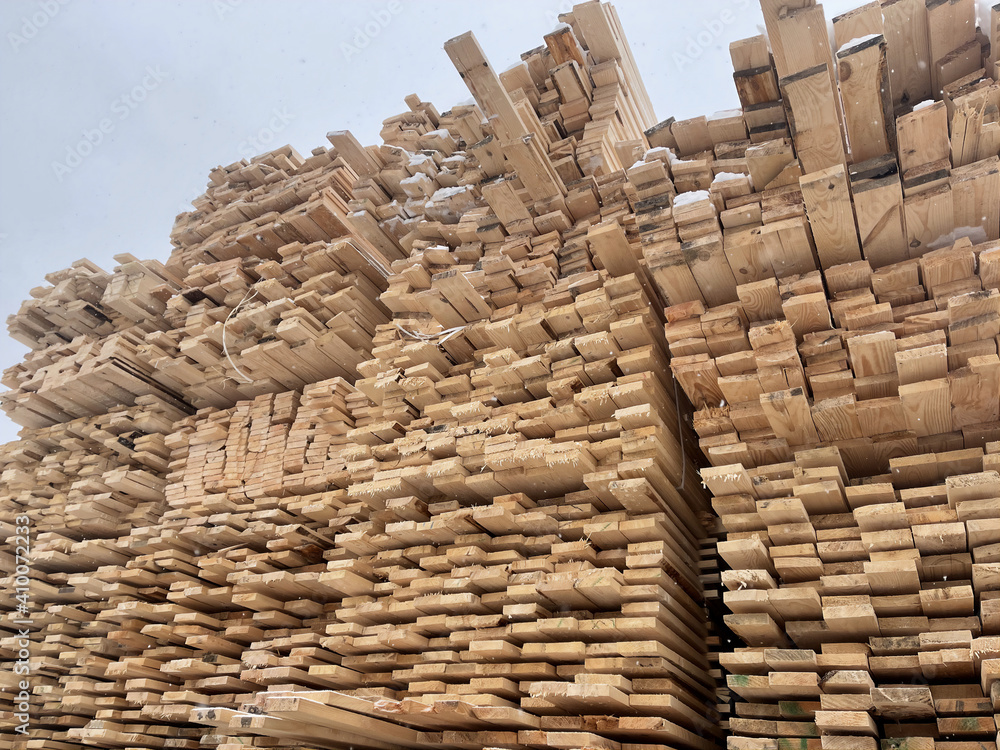 Close up of wooden boards on background of blue sky in snowy weather. Industrial natural timber building materials on building site in winter season. Close up of wooden boards on background of blue sky in snowy weather. Industrial natural timber building materials on building site in winter season.