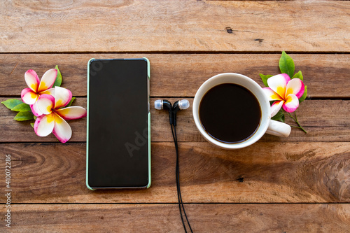 mobile phone ,hot coffee and flowers frangipani of lifestyle relax arrangement flat lay style on background wooden 