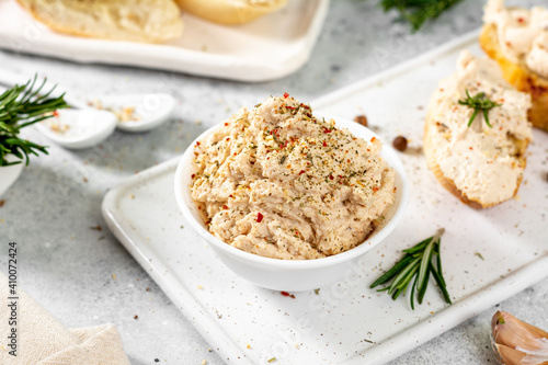Chicken pate in a white bowl on a light gray kitchen table. Homemade chicken fillet pate with seasonings on a light background