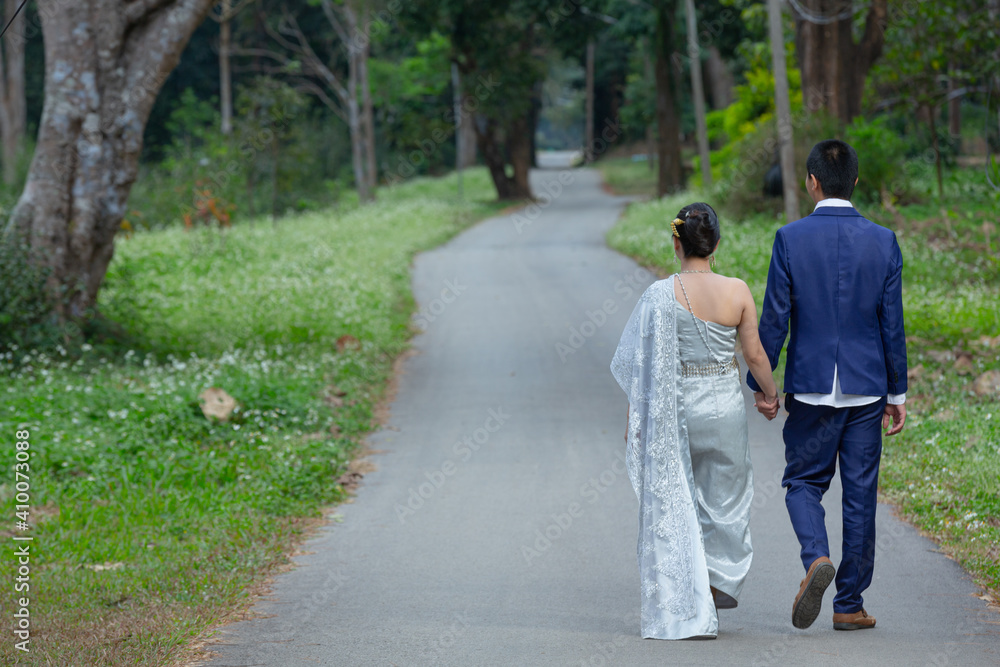 Young woman holding man hand while leading him on flower garden Young woman holding man hand while leading him on flower garden