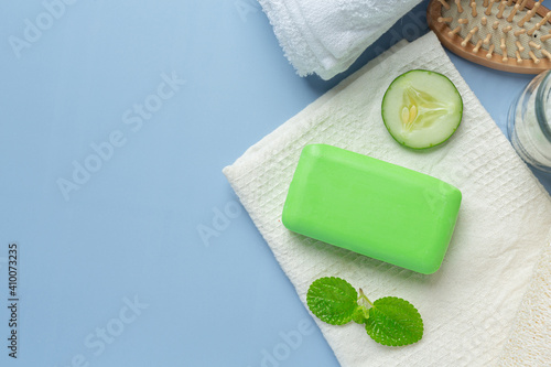 Cucumber slices and soap on light blue background