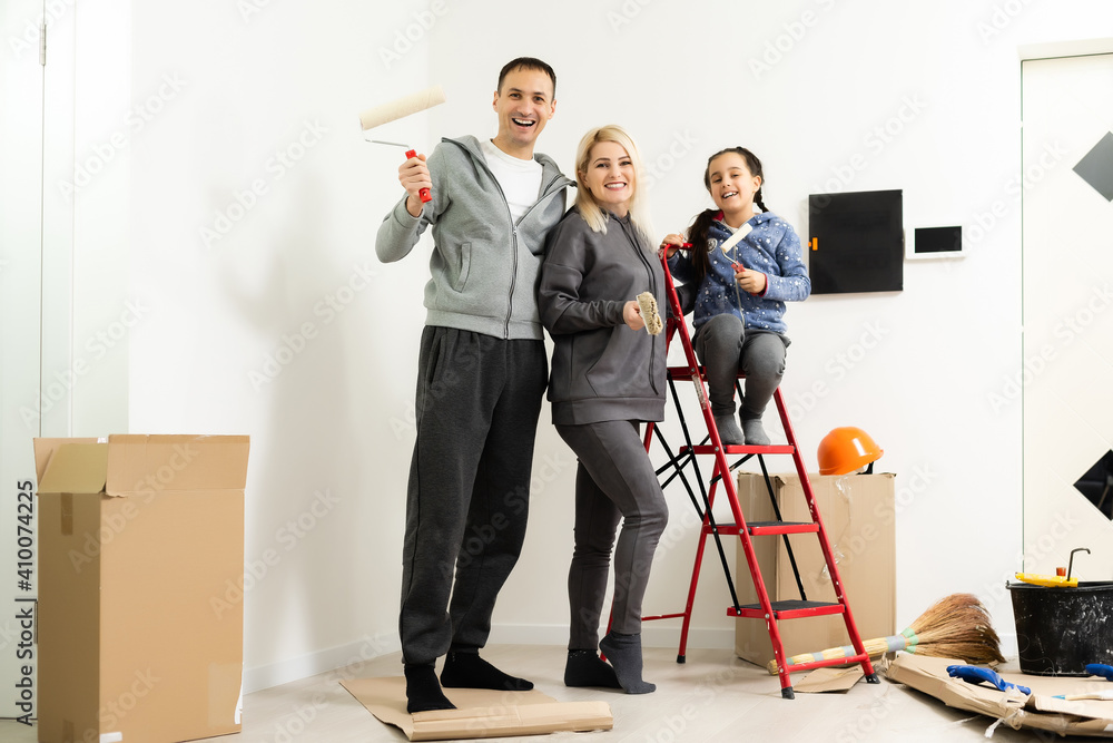 Happy young family with little daughter painting the wall