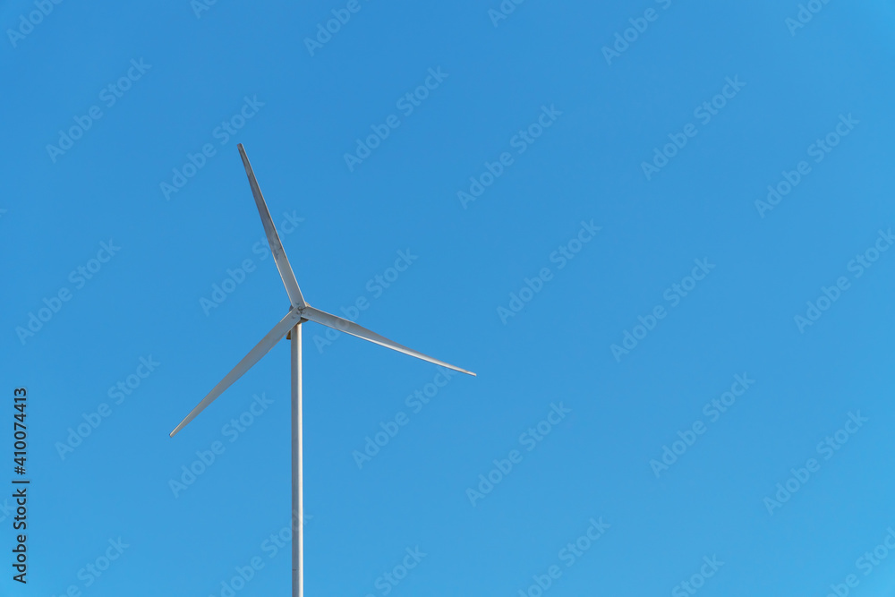 A small wind white turbine with a sky as a background.