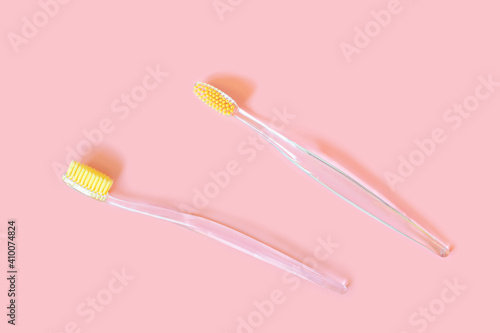 Toothbrushes with yellow bristles on a pink background. Oral hygiene  dentistry  teeth cleaning concept. Minimalism  top view  copy space.