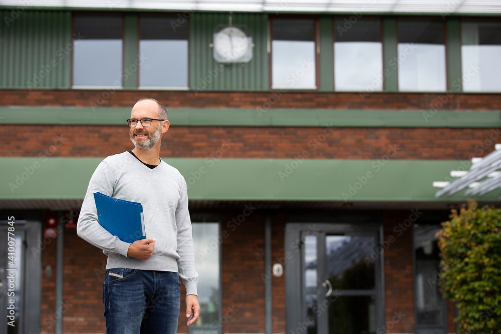 Teacher standing in front of school Teacher standing in front of school