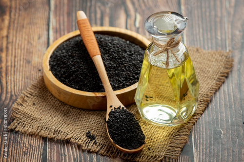 Sesame oil and raw black sesame seeds on dark background