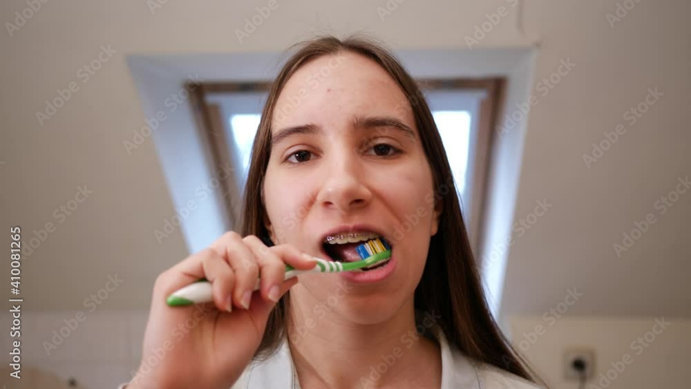Teenage kid girl with braces brush teeth in the morning at home preparing for school portrait view mirror camera Teenage kid girl with braces brush teeth in the morning at home preparing for school portrait view mirror camera