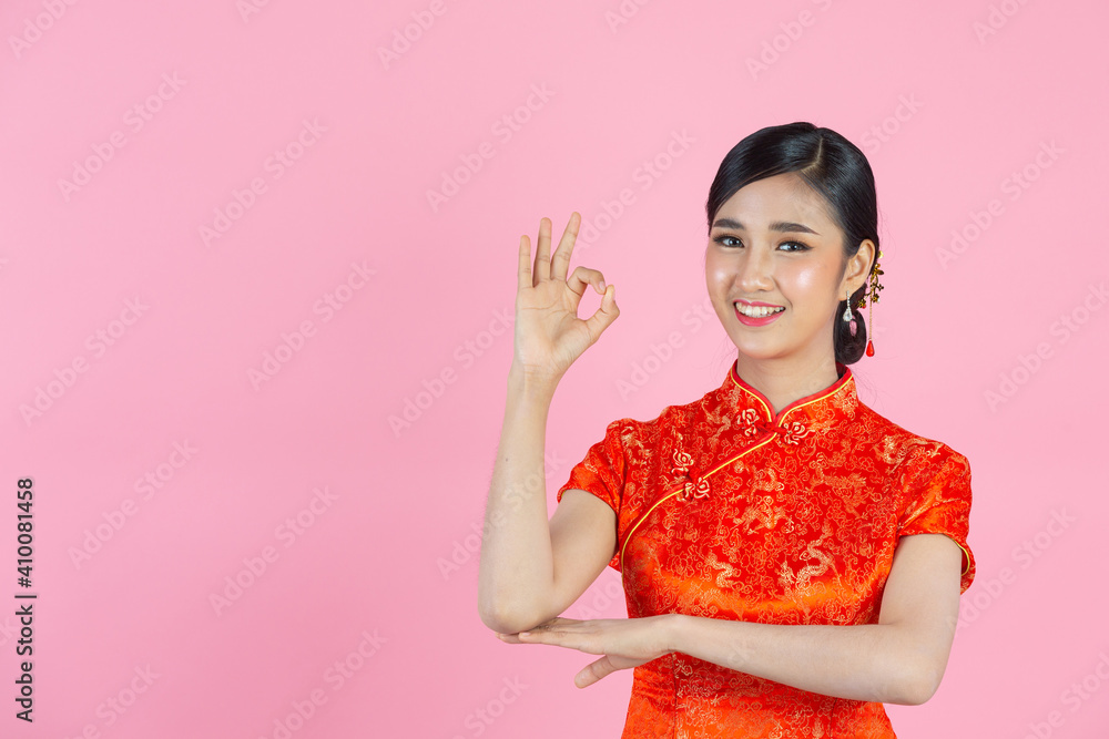 beautiful Asian woman happy smile and show something to you in chinese new year on pink background. beautiful Asian woman happy smile and show something to you in chinese new year on pink background.
