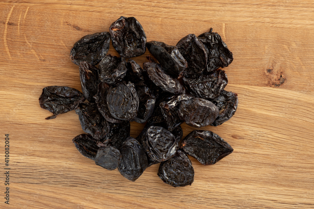 Pile of prunes, dry plums isolated on wood background. Pile of prunes, dry plums isolated on wood background.