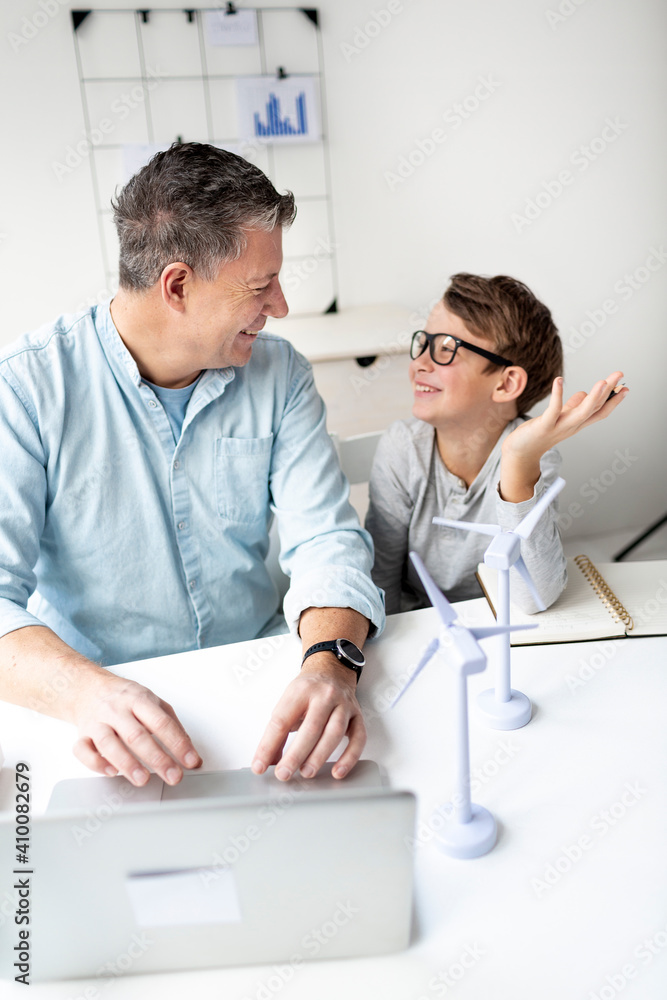 © epiximages - Wind energy as a source of energy concept. Father explains to son his area of ​​responsibility in wind turbine technology.