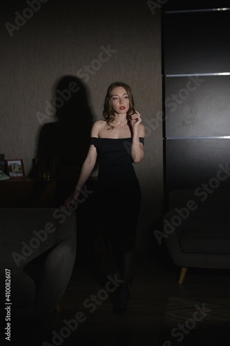  female model in a black dress shot in a noir style stands