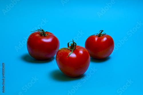 three  red tomato on turquoise background