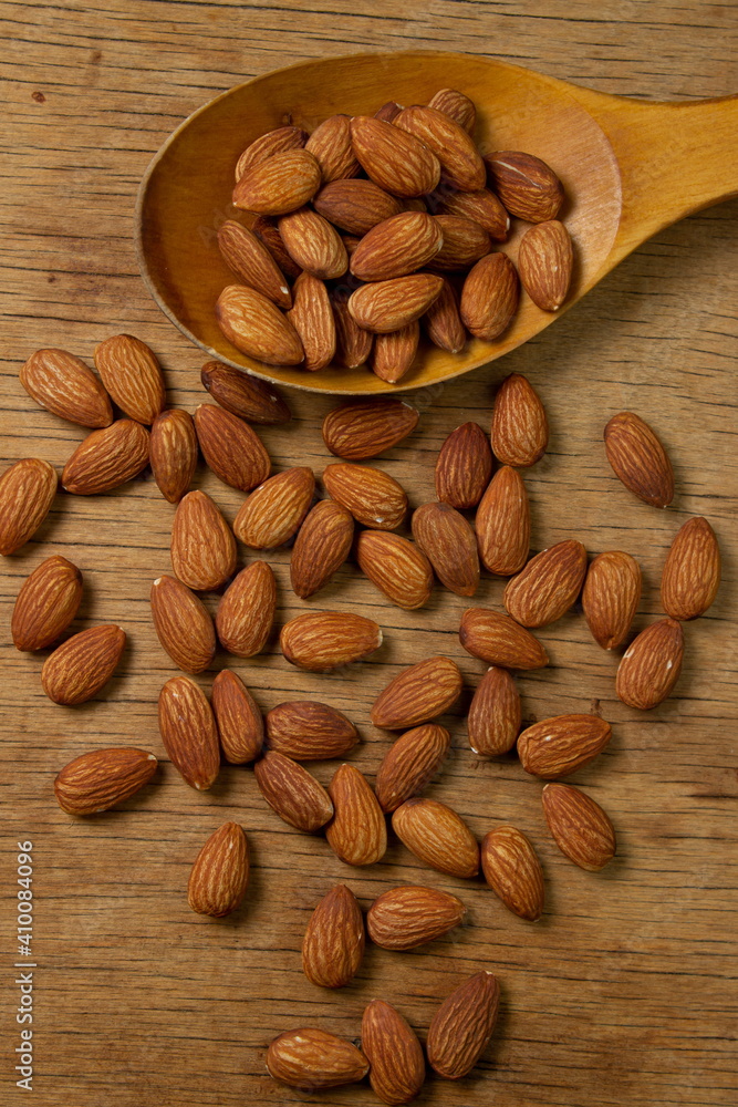 Almonds on a wooden background. Isolated almonds. Roasted almonds in a wooden spoon Almonds on a wooden background. Isolated almonds. Roasted almonds in a wooden spoon