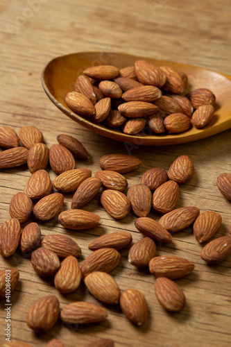 Almonds on a wooden background. Isolated almonds. Roasted almonds in a wooden spoon