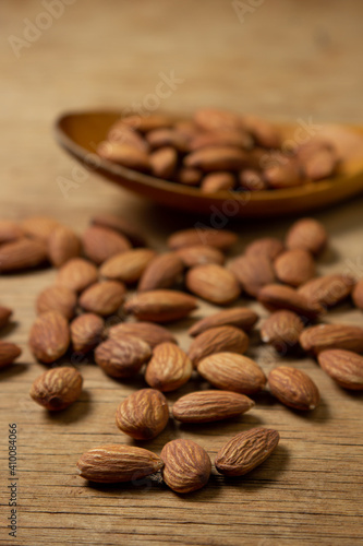 Almonds on a wooden background. Isolated almonds. Roasted almonds in a wooden spoon