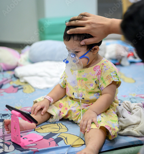 Asian baby was sick as Respiratory Syncytial Virus (RSV) in kid hospital. Thai little girl having inhaler containing medicine for stop coughing and disease flu. photo