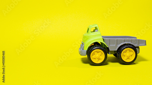 Toy truck car on a yellow background - construction equipment for children. Bright children's plastic toys, dump truck childhood.