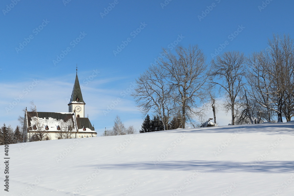 church on the horizon with trees in a snowy landscape