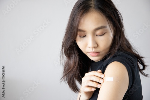 Asian woman receiving getting vaccinated immunity with bandage on her upper arm, concept of innoculation, vaccination, vaccine volunteer or vaccinated patient photo