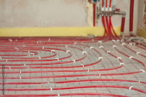 The red tubes of the underfloor heating system are mounted on the insulation.