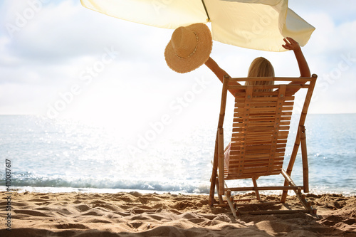 Fotografering Woman relaxing on deck chair at sandy beach. Summer vacation