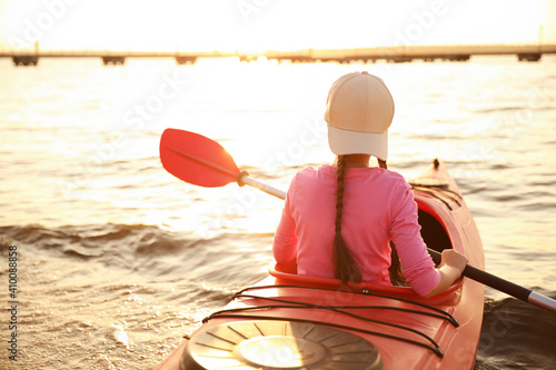 Little girl kayaking on river, back view. Summer camp activity