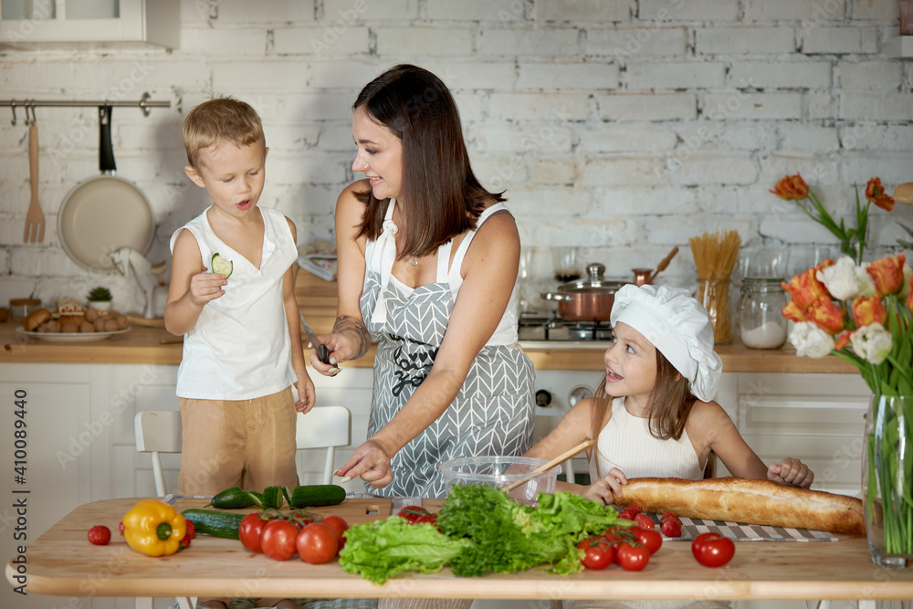 Mom cooks lunch with the kids. A woman teaches her daughter to cook from her son. Vegetarianism and healthy natural food