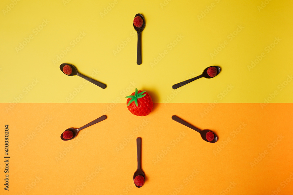 Squishy strawberry placed central on split of yellow and orange background. Flat lay arrangement of six chocolate spoons with fresh fruit -raspberries. Squishy strawberry placed central on split of yellow and orange background. Flat lay arrangement of six chocolate spoons with fresh fruit -raspberries.
