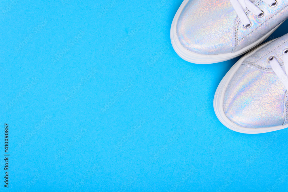 Silver sneakers on a blue background with place for text Silver sneakers on a blue background with place for text