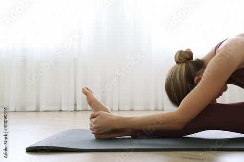 Young woman practicing head to knee asana in yoga studio. Janu Sirsasana pose photo