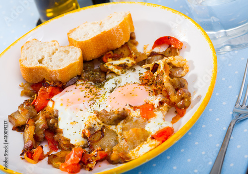 Delicious breakfast. Over easy fried eggs with chopped bacon, tomatoes and toasts..