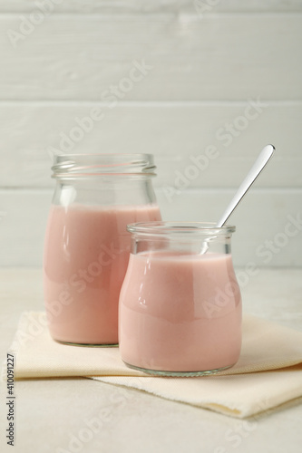Kitchen napkin with jars of yogurt on white textured background