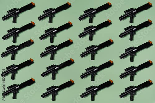 Pattern created of black rifle toys. A top view with pastel green background.