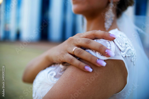 Beautiful bride showing her hand with ring by putting it on her shoulder. Wedding stock photo of married young girl with manicure and gold ring.
