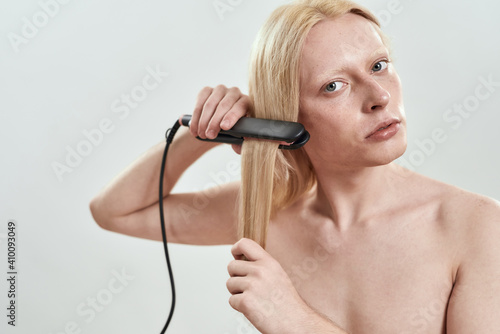 Young caucasian man applying hair straightener on hair