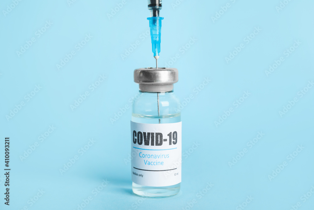 Filling syringe with coronavirus vaccine on light blue background Filling syringe with coronavirus vaccine on light blue background