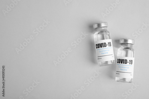 Vials with coronavirus vaccine on light background, flat lay. Space for text