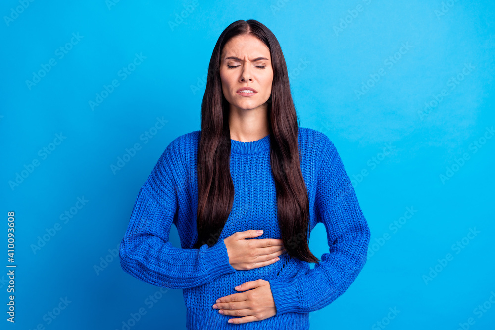 Portrait of brunette sad lady hold stomach wear blue sweater isolated on bright color background - obrazy, fototapety, plakaty 