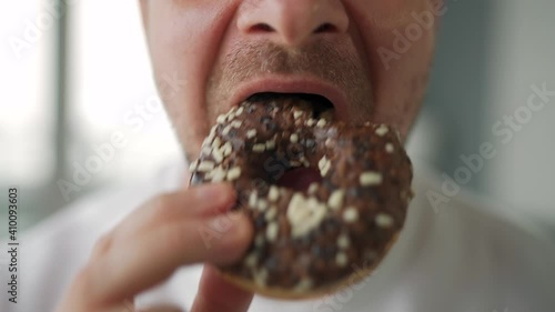 Man eating sweet chocolate donut. Close-up