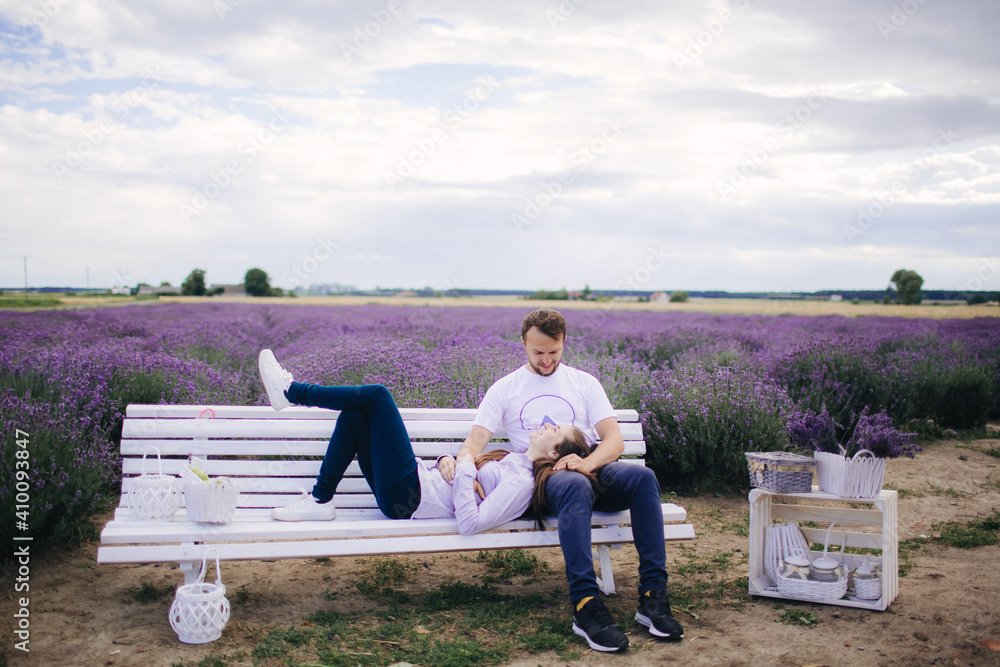 young couple sitting on a bench in a lavender field. man and woman are hugging outdoors. love story