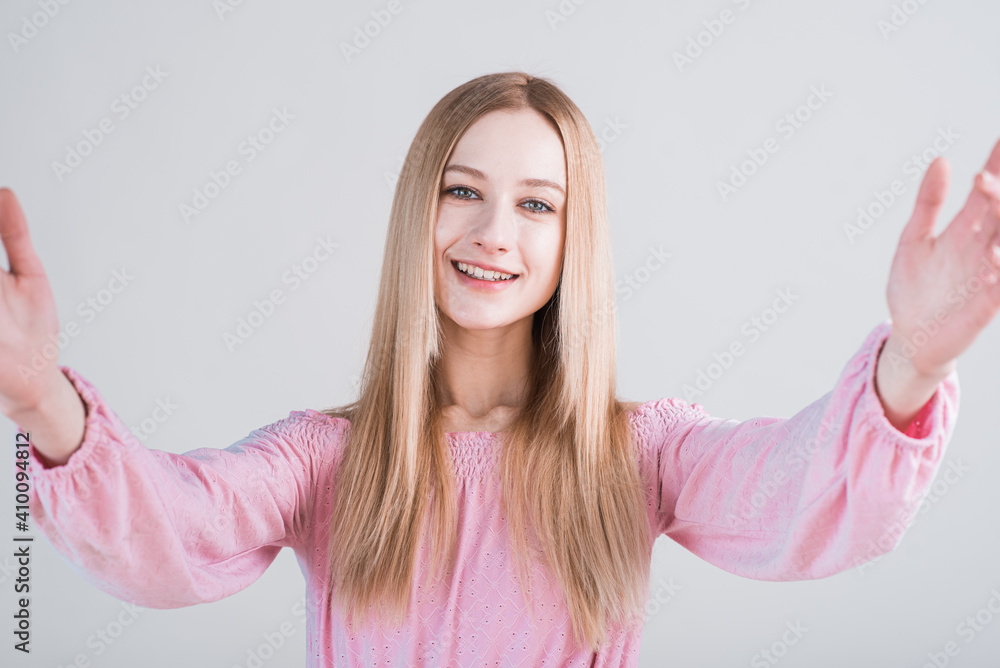 Portrait of young blonde woman with hug gesture in studio on white background